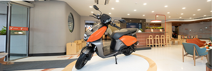 An image showcasing A VIDA electric scooter standing on the pedestal in the showroom representing the VIDA's phygital approach in E-scooters.